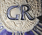 Gray-bodied salt glazed stoneware jug with applied round medallion molded with crowned GR cipher of King George I (1714-1727) or King George II (1727-1760). Just to the right of the angel’s wings are the initials SW (see detail).  The initials together on the right hand side in this manner generally indicate a 2 quart jug. Skerry and Hood (2009:50) date these SW marked jugs to the period between 1715 and 1740. Vessel 2317, from 18PR175.