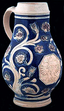 Gray-bodied salt glaze stoneware Jug with applied (sprigged) floral motifs with engraved (incised) stems and cobalt-blue and manganese purple decoration painted under the glaze.  Possibly similar to complete vessel shown here.  Vessel probably dates to second half of 17th century, based on the applied and incised motifs with cobalt blue and manganese, from 18CV60. Complete similar example from Private collection shown on right.