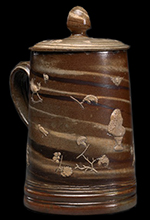 This covered salt glazed stoneware  tankard was made by Fulham potter John Dwight, circa 1685-1690. The figural and floral elements are sprig molded designs- This vessel is owned by the Nelson-Atkins Museum of Art, Kansas City, Missouri.  Accessed at http://en.wikipedia.org/wiki/John_Dwight_(potter). 