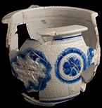 Gray-bodied salt glazed stoneware chamberpot  with applied rampant lion and stamped rosettes outlined in cobalt-blue  under the glaze.  Cordoned rim and base. Rim diameter. 6.70”; Base diameter: 5.50”; Vessel height:  5.75”; Object ID: 2602.