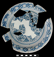 Plate painted in blue with floral motif and rim border of interlocking arcs.