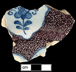 Plate powdered in manganese around white panels with blue floral motif.