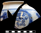 Debased scratch blue white salt glaze stoneware chamberpot decorated with sprig molded GR medallion and incised floral motifs.  Manufactured c. 1770-1800. Rim diameter:  8.00”