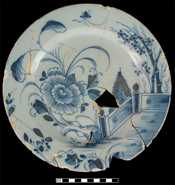 Plate painted in blue with floral sprays and a large central peony, a fence, and bamboo along the upper right side from the Brookes Inn 18PR386.