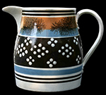 Ironstone jug with offset decoration against black slip. Patterns created by dipping a cookie-cutter-like tool into slip and stamping or pressing it onto the body of the vessel. c. 1840s or later,  7 inches in height - from a private collection.