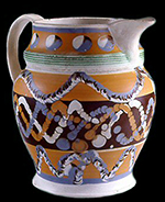 Pearlware jug. Vessel shows three uses of  the three-chambered slip cup: cat's eye, cable and an unnamed motif where the 3 quills were separated and dragged on the pot surface, c. 1830. 9 inches in height - from a private collection.