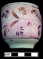 Refined white earthenware cup with painted floral luster decoration against pink luster band. Rim diameter: 3.00”, Base diameter: 1.50”, Vessel height: 2.50”. Vessel #: 61. 18BC56