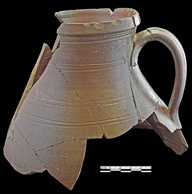 Brown bodied salt glaze stoneware pitcher with incised bird with small x-shaped marks in front the of the bird’s beak, resembling insects. Vessel also marked with an incised and stylized “2”  for a two gallon capacity mark.  The decoration on this vessel has been attributed to the workshop of Chester Webster (1799 -1882). Webster came to Fayetteville, North Carolina to make pottery around 1830. By 1840, he was in Randolph County and working for potters Solomon and B. Y. Craven. This vessel is believed to date to the 1840s or 1850s, based on the color and decorative style (Hatch et al. 2017: 84).  