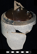 North American buff bodied stoneware jug with Albany slipped shoulder, neck and handle.  Bristol glaze covers the cylindrical body.  Damaged by burning. Vessel diameter: 6.00”, Vessel V-17 from 18MO609.