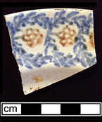 Cut sponge plate with brown and blue floral motif. Rim diameter: 9.00”