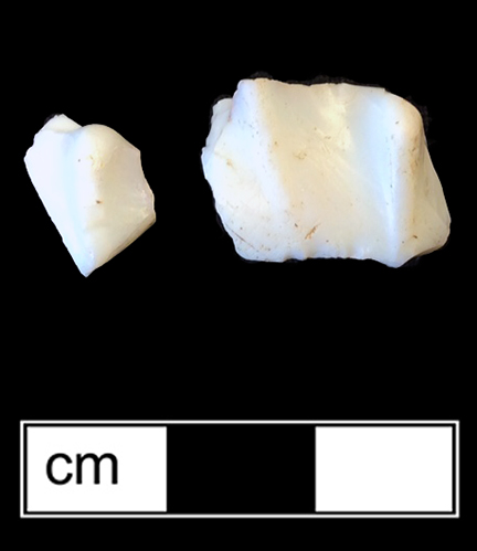 Opaque white (lattimo) glass hollow vessel with pattern molded ribs.  Although these fragments are too small to make a positive identification, the ribs may have been part of a form of decoration known as “nipt diamond waies” (Lanmon 2001:82).  In this technique, adjacent vertical ribs were manipulated with pinchers to form a diamond pattern (Corning Museum of Glass).  This form of decoration was used between circa 1690 and the 1740s (Hughes 1956:211). Lots 195 and 39. 18ST390.