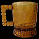 Complete amber glass “Bird on Branch mug; part of Beaded Handle set produced by the Bryce Brothers in the 1880s, when the company may have been known as Bryce, Walker & Co. The Brewhouse mug is missing its pleated skirt base from a private collection.