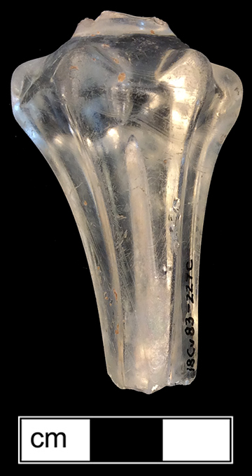 Colorless leaded glass wine glass stem fragment.  6-sided pedestal stem with diamonds on the shoulders.  Also called “Silesian”.  Pedestal stems typical of 1715-1765 period (Bickerton p. 19).  Style introduced c. 1714 with ascension of King George I (Bickerton p. 24).  