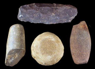 Four indigenous stone tools including a pestle, abrader and gorget.