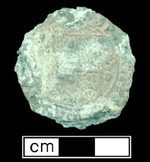 Figure 2 Park ranger in tan uniform holding measuring tape next to heavily deteriorated shipwreck timber fragments standing upright against white building.