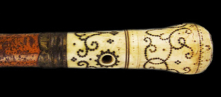 Cylindrical end of a walking stick with a floral and C-scroll decorative motif.