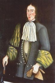 Stern looking man in a many-buttoned coat, holding a pair of gloves and a walking stick.