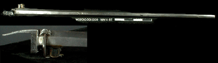 Figure 1 Full-length archaeological musket barrel displayed against black background with identification label 