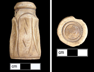 Side view of cylindrical ivory object with carved linear decorations. View of the circular base of the ivory inkhorn.