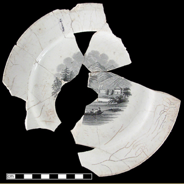 Fragmented ceramic plate, with central decoration of group of people in a canoe on a lake with mountains in background.