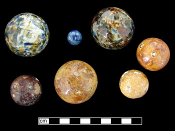 Seven stoneware marbles in vareigated colors of blue, yellow and brown.