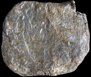 Flattened oval lead disc showing disorganized pattern of scratched lines.