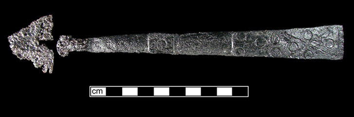 Figure 1 Archaeological iron door latch fragment photographed against black background with centimeter scale bar.