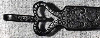 Figure 3 Close-up photograph of ornate iron strap hinge terminal with decorative pierced scrollwork and punched circular decorative elements.