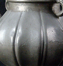 Figure 4 Close-up detail photograph showing the curved, ridged surface of a deteriorated metal object with a grayish patina.