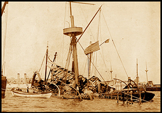 Sepia colored photograph of the USS Maine sinking in 1898 after her destruction.