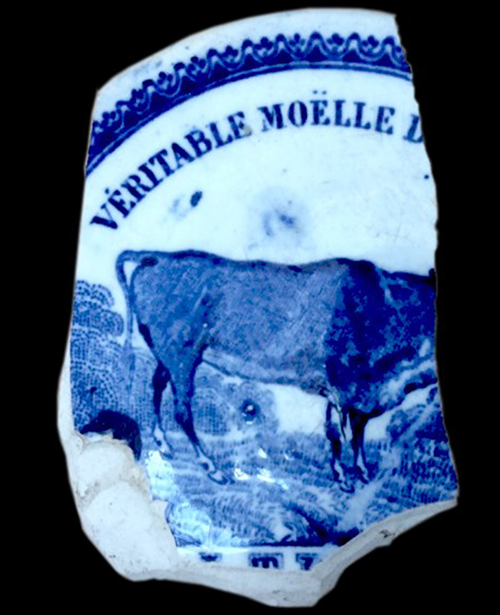Broken ceramic pomade lid printed in blue with the image of an oxen.