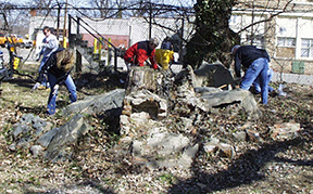 Photograph of archaeologists working to pick up stone fragments.