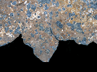 Close up photograph showing traces of gilding on a white metal coffin handle.