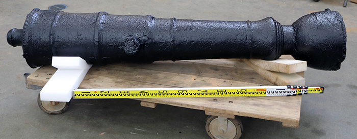 Iron cannon with black coating after conservation treatment with a scale bar.