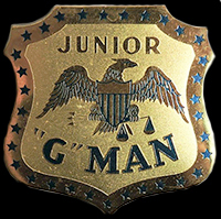 Shield-shaped brass badge with decorative star border showing an eagle with spread wings above the text 'JUNIOR G MAN'.