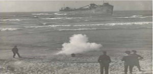 Black and white image showing a large cloud of smoke around a black dot that
is likely a Lyle gun. Gun is sitting on a beach facing a large ship in the water with four
people in the foreground watching.