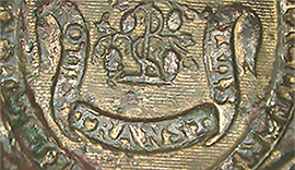 Magnified image of a button showing an engraved banner decoration that reads “Qui Transt Sust”.