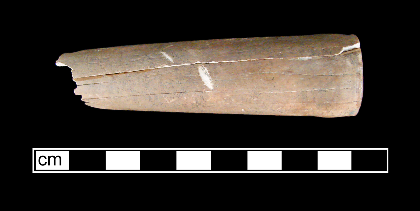 A light-colored knife handle with no blade. The handle is cracked lengthwise three times and may be stained with soil. The photo scale indicates the artifact is about 8 centimeters long.