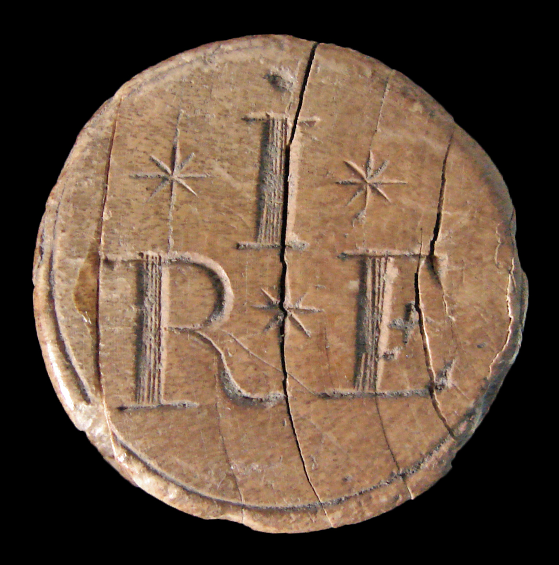 Close-up image of the blunt end of the handle with letters and stars engraved into the end. The material appears to be cracking in evenly spaced curved lines.