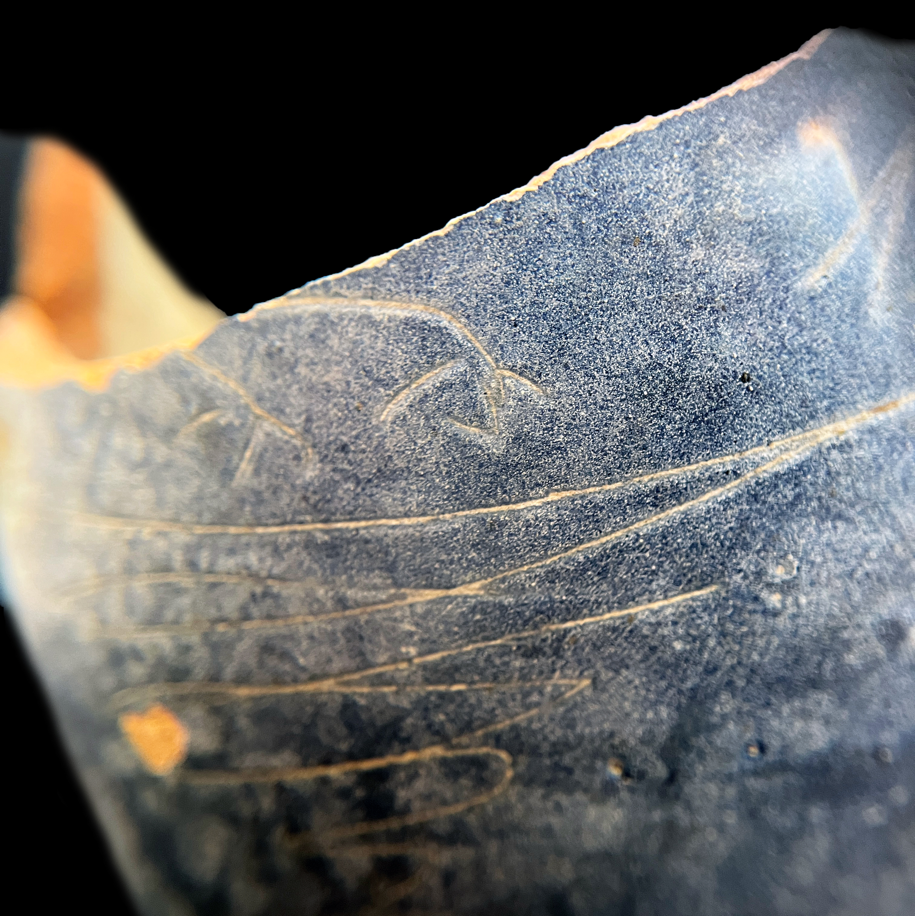 Detail image of an incised depiction of birds feet decoration on the side of the bottle.