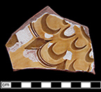 North Devon Sgraffito indeterminate vessel, probable dish. White slip over red earthenware body, with lead glazed interior.  Incised motif. Some of the lead glaze and slip have  worn away from this sherd.