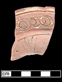 North Devon Sgraffito plate with incised repeating spiral (curlicue) motif along rim.  White slip over red earthenware body, with lead glazed interior. Rim diameter 7”. Most of the lead glaze and white slip have been worn away from this vessel, showing damage from water erosion. Rim motif similar to Vessel 26 depicted in Grant (1983), from a context of circa 1665. Lot 11 – Beach find.