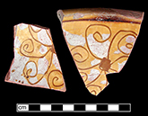 North Devon Sgraffito bowl. White slip over red earthenware body, with lead glazed interior.  Incised floral (or spiral asterisk) motif.  Approximately 9.5” rim diameter. Some of the lead glaze has  worn away from this sherd. Vessel 38.  Lots 642, 720, 730, 874, 881. (Feature 12).  The floral motif on this vessel is very similar to examples found in a circa 1670-1680 context at Jamestown and discussed in Outlaw (2002).