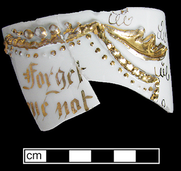 European hard paste porcelain mustache cup  with molded decoration and gold gilt band embellishments and text &ldquo;Forget me not&rdquo;.  Printed marked base &ldquo;Made in Germany&rdquo; in circle, providing date of post 1891 for manufacture. 3.5&rdquo; rim diameter.