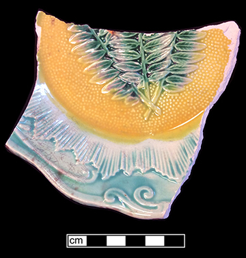 Molded plate with fern motif. Rim diameter: 8.00”. The underside of this vessel has a mottled brown and green lead glaze.