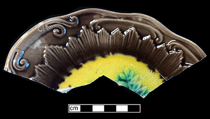 Molded plate with fern motif. Rim diameter: 8.00”.The underside of this vessel has a mottled brown and green lead glaze.