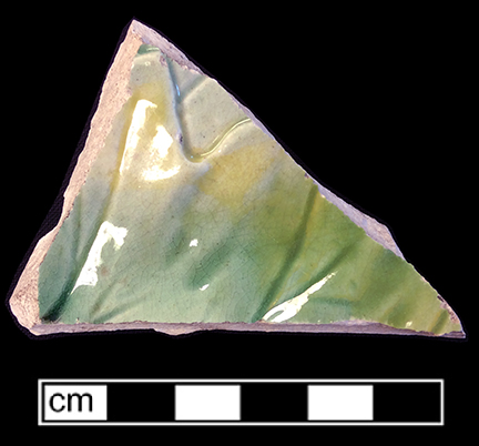 Molded flat vessel with leaf motif. The underside of this vessel has a mottled yellow and green lead glaze. 