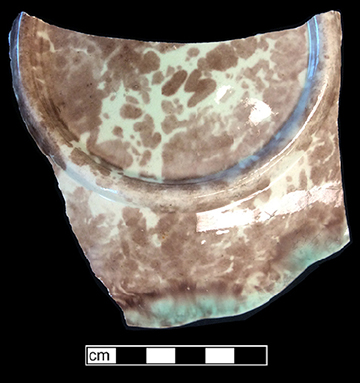 Molded plate with fern motif. Rim diameter: 8.00”. The underside of this vessel has a mottled brown and green lead glaze.