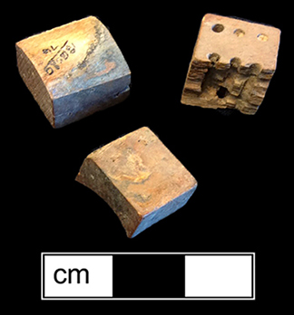 Unfinished bone die.  This example is one of seven unfinished dice or game pieces recovered from this privy.  The die has been shaped and markings made for the placement of the dots, for later drilling.  Each of the pieces has split or shows damage that led to its being discarded before completion. 18BC80