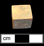 Unfinished bone die.  This example is one of seven unfinished dice or game pieces recovered from this privy.  The die has been shaped and markings made for the placement of the dots, for later drilling.  Each of the pieces has split or shows damage that led to its being discarded before completion. 18BC80